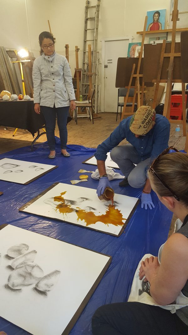 Hilmi pouring the shellac over the charcoal drawing